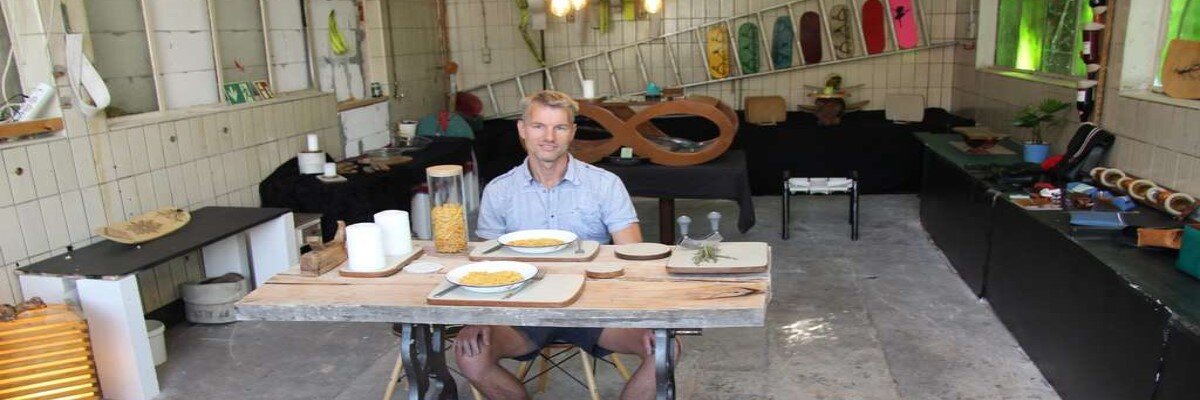Michael Bischoff mit kurzen blonden Haaren sitzt an einem Tisch gebaut aus einer Wäschemangel